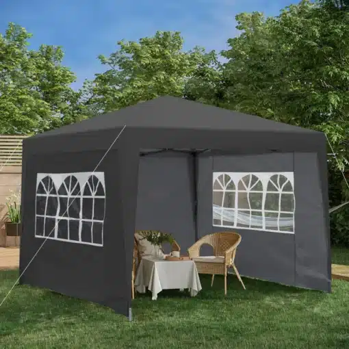 Pop up aiatelk 3x3m veekindel UV50+ | E-pood Tootemaailm Must Pop up aiatelk 3x3m veekindel UV50+ on paigaldatud rohelisele murule, ümbritsetud puude ja sinise taeva taustaga. Telgil on akendega seinad ja sees paistab laud toolidega.