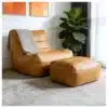 Kompaktne ergonoomiline jalatoega tugitool elutuppa | E-pood Tootemaailm Elegantne pruun nahast kompaktne ergonoomiline jalatoega tugitool elutuppa, dekoratiivse halli tekiga, mille taustal on suur roheline taim ja heledad seinad.