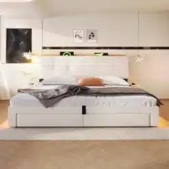 Moodne voodi panipaigaga, USB-C ja LED valgustus, 180x200, valget värvi peats ja raam, hele beež kate, voodi mõlemal küljel öökapp ning seinapildid taga, valguslüliti ja dekoratiivsed esemed.