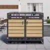 Õues asuvad prügikastid, mis on valmistatud tugevast metallraamist ja puidust paneelidest, varustatud hüdraulilise kaane ja lukuga. Taustal on modernne aed terrassimööbliga ja avar aknavaade.