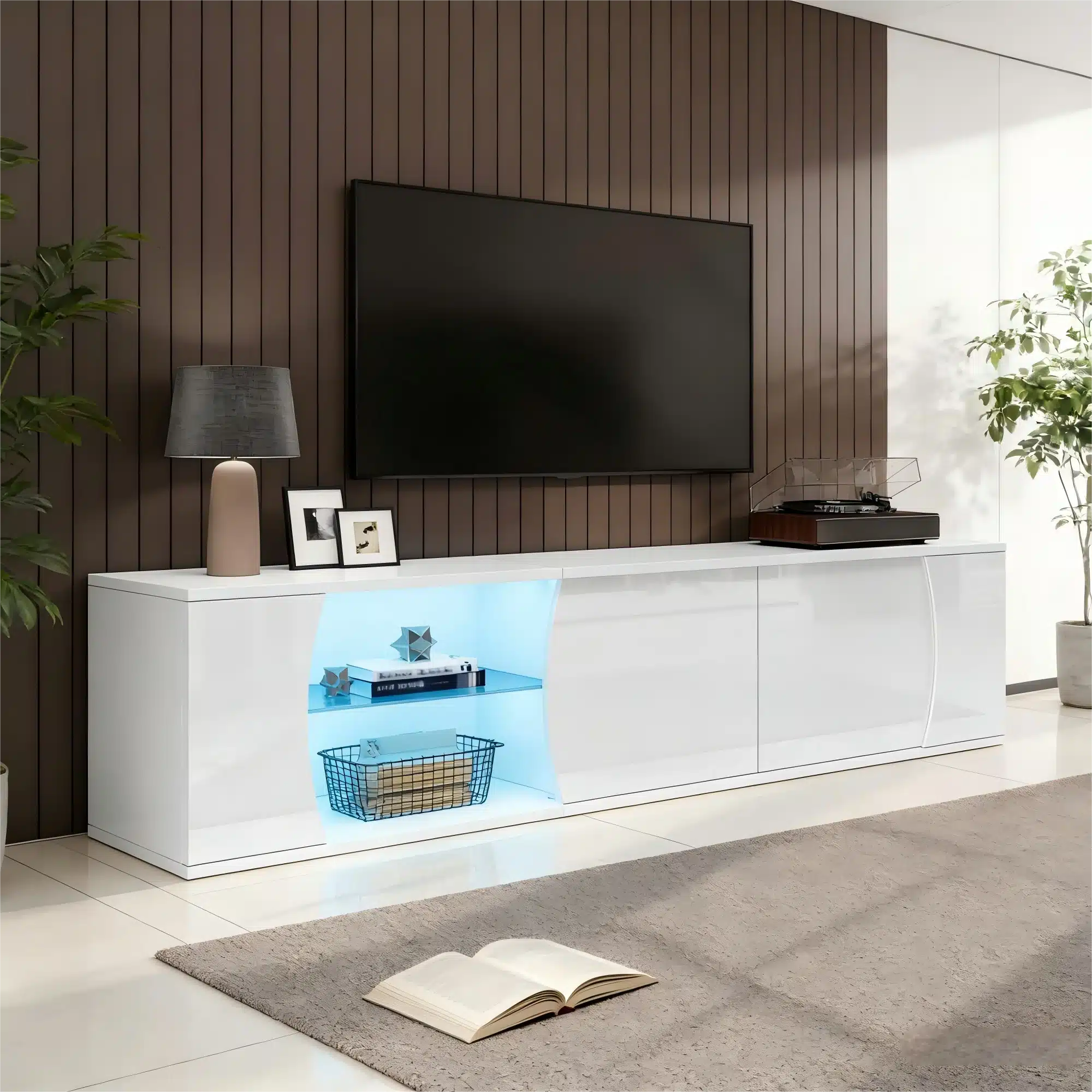 TV-alus LED-valgustusega, valmistatud karastatud klaasist ja MDF-ist, 180 cm lai, hele valge viimistlus, kaasaegses elutoas tumedate pruunide seinte taustal, millel on avatud riiul sinise LED-valgustusega, mille peal on dekoratiivsed esemed ja raamatud.