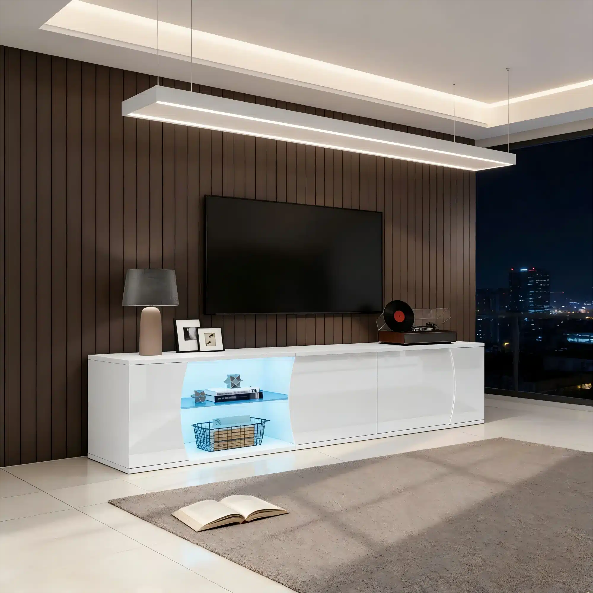 Kaasaegne valge TV-alus, mille pikkus on 180 cm, sisaldab LED-valgustust ja karastatud klaasist riiuleid. Alus on paigutatud avarasse elutuppa, mille taustal on pehme pruun puitsein. Ülemine riiul on valgustatud sinise valgusega, lisades stiilse aktsendi kogu ruumile.