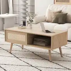Diivanilaud liugustega punutud ja täispuidust jalad 105cm, helepruuni tooni, modernses elutoas mugavalt sisustatud vaiba peale asetatuna, taustal heledad diivanipadjad.