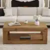 Diivanilaud kahe avatud riiuliga, vastupidav MDF, hele | E-pood Tootemaailm Diivanilaud kahe avatud riiuliga, vastupidav hele MDF materjal, pehme valge diivani ja kamina taustal, laual raamat, kohvitass ja valged lilled lillepotis.
