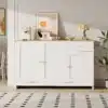 Stiilne valge kummut kööki, millel on kolm ust ja üks sahtel, kaunistatud minimalistliku dekooriga avaras ja helges ruumis.