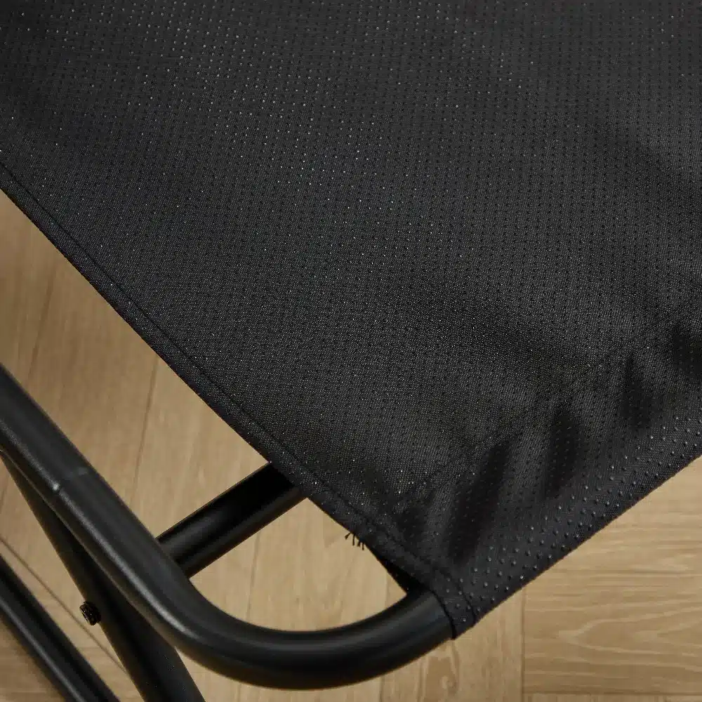 Lähivõte õuetoolist musta raamiga ja valge pehmendusega, keskendudes mustale kangale ja tugevatele metallist jalgadele, mis asuvad heledal puidust taustal.
