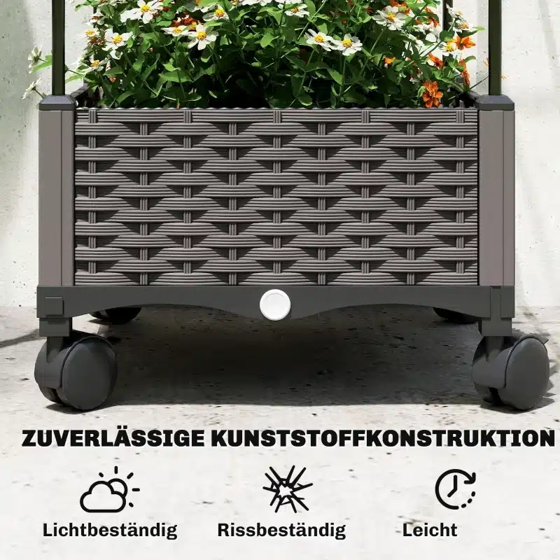 Kõrge aiakast trellisega ratastel, äravooluavaga 40x40x185, millel on helepruun kunstmaterjalist punutise disain ja mustad rattad. Kastis kasvavad õieilu pakkuvad väiksed valged ja oranžid lilled, taustal hele kivisein.