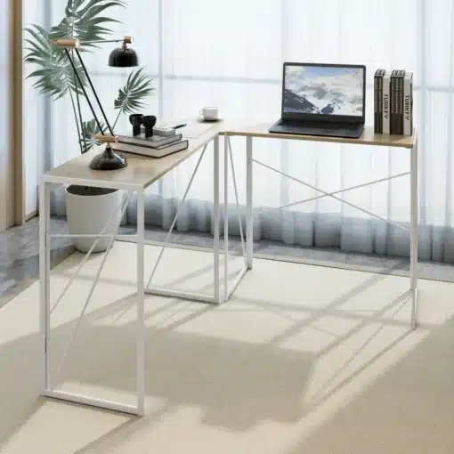 Stiilne nurgakujuline arvutilaud kodukontorisse, hele puit, minimalistlik disain, must lamp ja sülearvuti laual, kõrval toataim ja aknakardinad, valgusküllane interjöör.