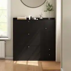 Must jalatsikapp kolme klapiga koos istumispingiga, mis seisab valgusküllases ruumis puidust põrandal, taustal hele sein ja aken.