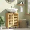 Vannitoakapp bambusest liugustega, reguleeritavad riiulid | E-pood Tootemaailm Elegantne vannitoakapp bambusest liugustega, sees reguleeritavad riiulid, mis asub valgusküllases ruumis. Taustal roheline sein ja valge kraanikauss kapil peal.