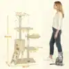 Kassipuu koopaga, mänguasjad ja trepp | E-pood Tootemaailm Kassipuu koopaga, mänguasjad ja trepp, hele beež, kõrgusega 134 cm, seisab toa neljavärvilise tausta ees. Toote kõrval on mõõtmed esile toodud ja läheduses on naine võrdluseks ning kass istub põrandal.