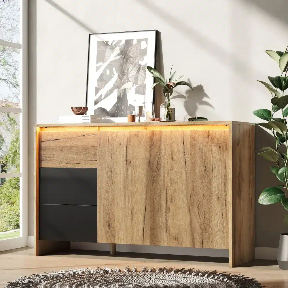 Elegantselt disainitud puidust kummut LED valgustusega, mõõtudega 120x76x40 cm, asetatud moodsasse interjööri koos taimedega taustal ja dekoratiivse kunstiga pinnal.