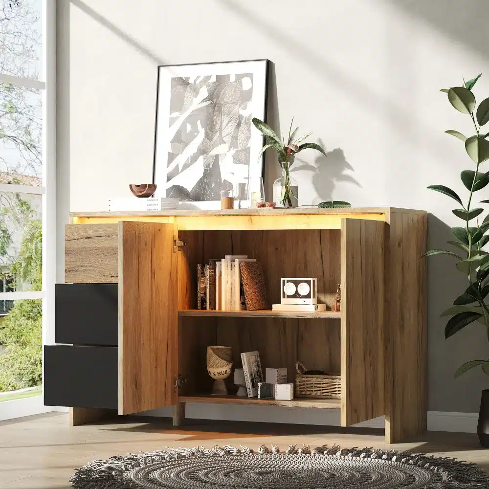 Elegantselt kujundatud puidust disain kummut LED valgustusega, mõõtmetega 120x76x40 cm. Kummut seisab elutoas, osaliselt avatud uste ja sahtlitega, eksponeerides sisseehitatud LED-valguse all lugemismaterjale ja dekoratiivseid elemente. Taustal on neutraalsed seinad ja suur taim, loomas hubast atmosfääri.