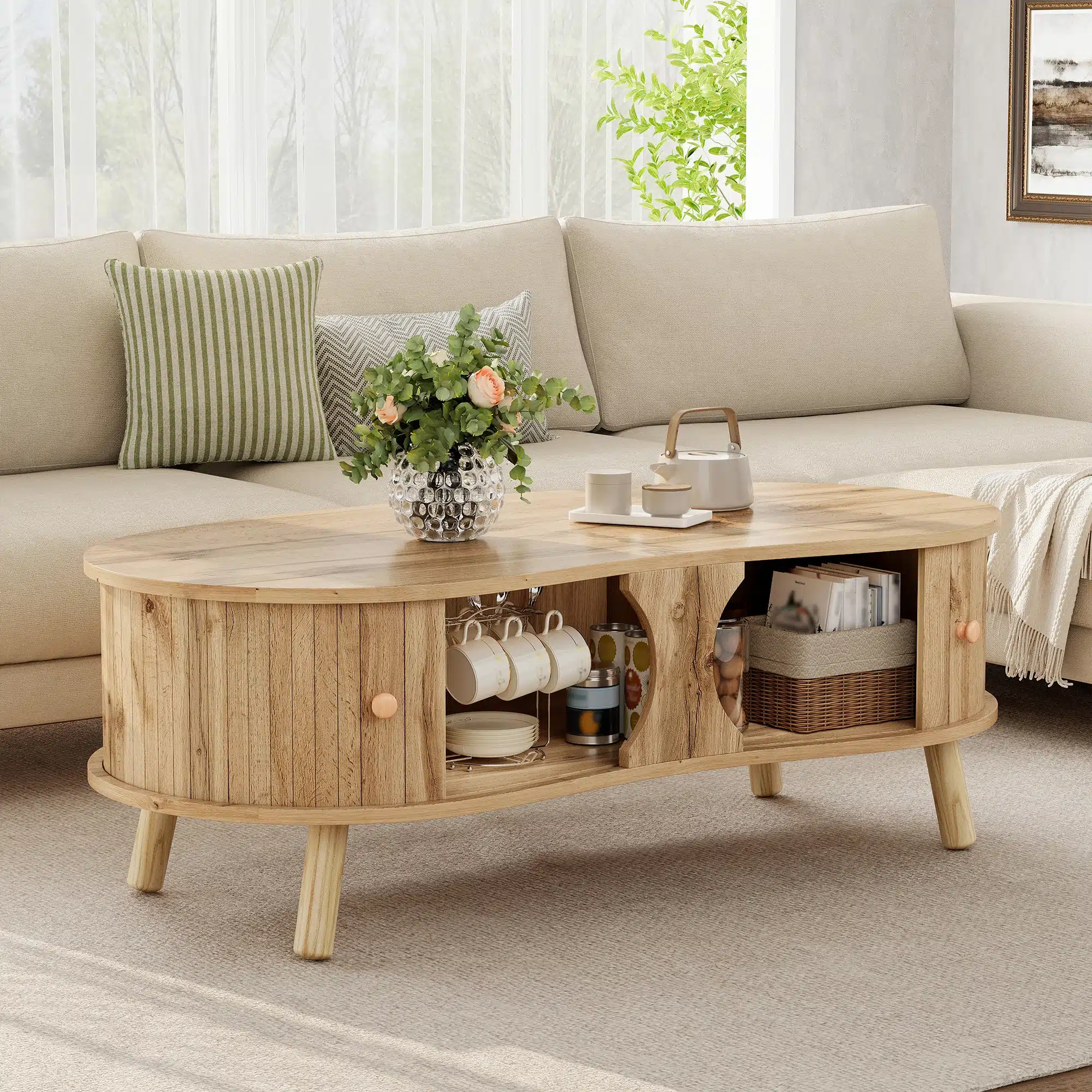 Diivanilaud puidumustriga, liugustega ja täispuidust jalgadega, paikneb elegante beeži diivani ees. Laud on kaunistatud roheka lillevaasi ja teekomplektiga. Looduslik valgus täidab ruumi tänu suurtele akendele.