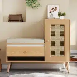 Puitviimistlusega kingapink, millel on rotangist uksed, valgest pehmendusega iste ja avatud sahtlid, minimalistlikus esikus valge vaiba taustal.