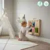 Seinale kinnitatav raam Montessori tegelustahvlitele lastele | E-pood Tootemaailm Väike laps mängib seinale kinnitatud puidust tegevuspaneeliga mängutoas