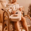 Laste ukulele mängupill 4 keelega alates 3. eluaastast | E-pood Tootemaailm Väike laps hoiab valget ukulelet punutud toolil istudes