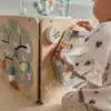 Montessori tegeluskuubik lastele 12+ kuud | E-pood Tootemaailm Laps mängib puidust tegevuslauaga, millel on kujundid ja peegel