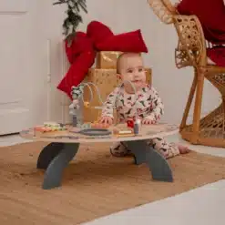 Beebi mängib madala puidust tegevuslaua juures koduses toas