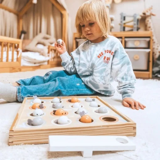 Montessori kalapüügi mäng lastele | E-pood Tootemaailm Väike laps mängib põrandal puidust sorteerimismänguga, millel on munakujulised osad.