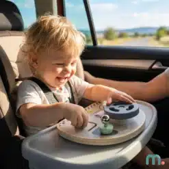 Väikelaps autos turvatoolis mängimas puidust tegevuslauaga