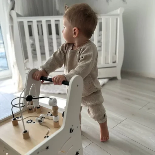 Puidust käimistugi ja õppelaud 6 in 1 lastele | E-pood Tootemaailm Väikelaps seisab ja hoiab kinni puidust tegevusmänguasjast toa põrandal