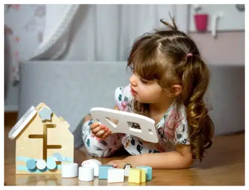 Puidust sorteerimismaja lukkudega Montessori mänguasi lastele | E-pood Tootemaailm Laps mängib puidust kujundusmänguasjaga põrandal