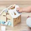 Puidust sorteerimismaja lukkudega Montessori mänguasi lastele | E-pood Tootemaailm Laps mängib puidust kujundisorteerija majakujulise mänguasjaga põrandal