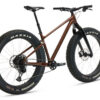 Pruuni ja musta raamiga fatbike, paksude rehvide ja ketaspiduritega, külgvaates valgel taustal