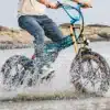 Kokkupandav elektrijalgratas Fiido M1 Pro roheline | E-pood Tootemaailm Inimene sõidab läbi vee fatbike-tüüpi elektrirattaga, pritsmed lendavad ümber ratta