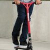 Trikitõukeratas Razor Beast V6 lastele | E-pood Tootemaailm Punane Razori tõukeratas, millel seisab inimene ja hoiab juhtrauast kinni õues betoonpinnal.
