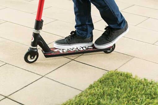 Trikitõukeratas Razor Beast V6 lastele | E-pood Tootemaailm Inimene sõidab musta punaste detailidega tõukerattaga plaatkattega pinnal