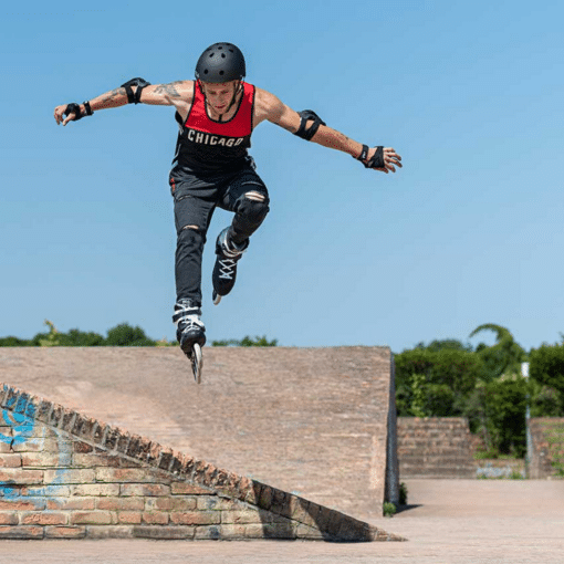 Ruluisõitja hüppab ramplt väljas, kandes kiivrit ja kaitsmeid, taustal sinine taevas