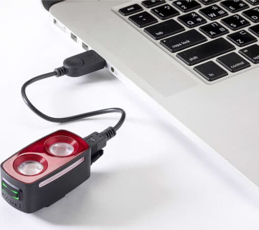 USB-ga ühendatud väike kahe LED-lambiga must punase ülaosaga seade sülearvuti kõrval