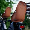 Laste jalgrattatool Urban Iki Bio pakiraamile | E-pood Tootemaailm Kaks pruunist seljatoega jalgrattatooli rattahoidikul, tagantvaade õues