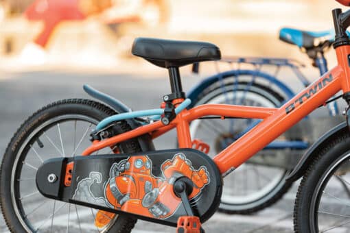 Oranž laste jalgratas külgvaates musta ketikattega