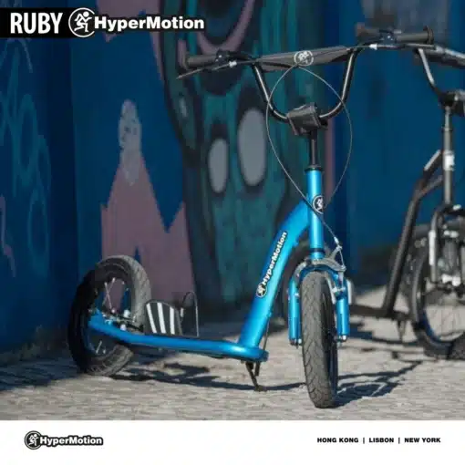 Laste tõukeratas HyperMotion RUBY 12.2 käsipiduritega | E-pood Tootemaailm Sinine HyperMotioni tõukeratas linnatänaval, musta juhtraua ja väikeste ratastega.