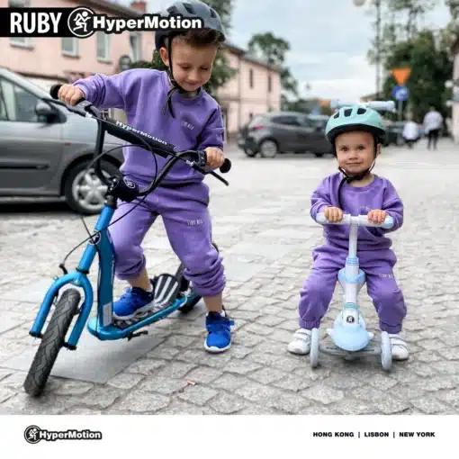 Laste tõukeratas HyperMotion RUBY 12.2 käsipiduritega | E-pood Tootemaailm Kaks last sõidavad HyperMotioni tõukerattal ja tasakaalurattal linnatänaval, mõlemad lilla dressikomplektiga