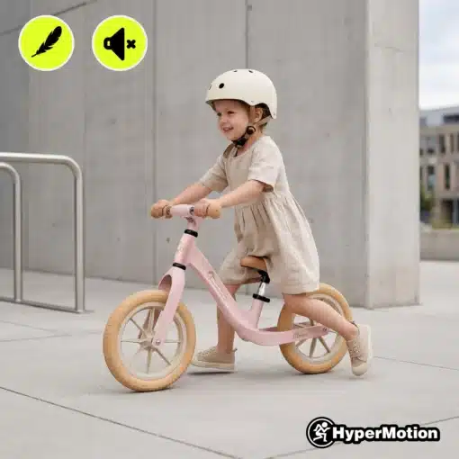 Laste tasakaaluratas HyperMotion Bloom magneesiumraamiga | E-pood Tootemaailm Laps sõidab roosal tasakaalurattal kiivriga linnakeskkonnas