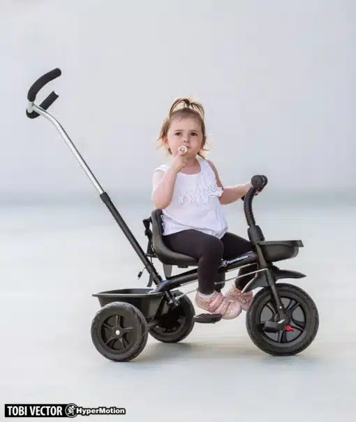 Laps istub mustal kolmerattalisel lükataval rattal, millel on käepide ja jalatoed