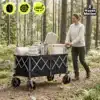 Kokkupandav transpordikäru 250 l ja kandevõimega 100 kg | E-pood Tootemaailm Must suurte ratastega veokäru metsarajal, mida lükkab naine; kärus on tekk, nõud ja termos