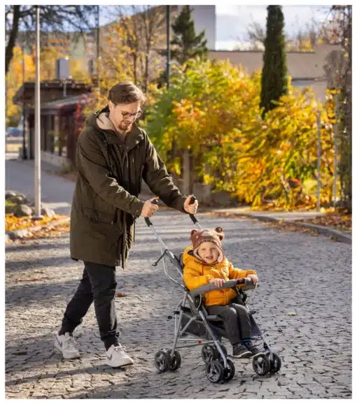 Kokkupandav lapsekäru turvarihmade ja kaitsepiirdega | E-pood Tootemaailm Mees lükkab sügisesel tänaval last halli jalutuskäruga