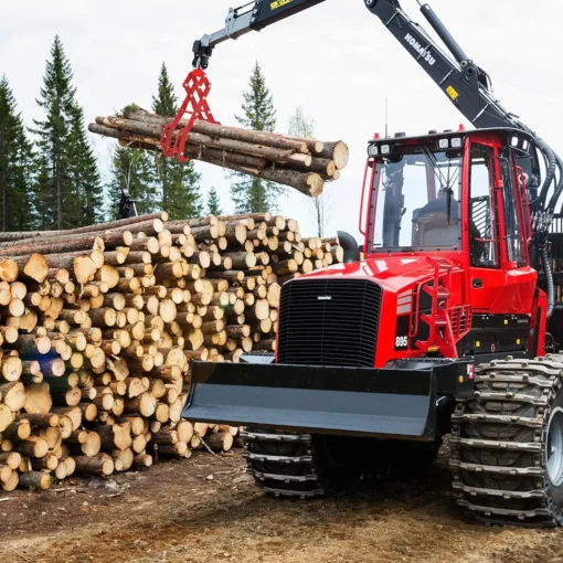 Punane Komatsu metsamasin tõstab haaratsiga palke virna kõrvale