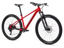 Punane hardtail maastikuratas esikahvli, ketaspidurite ja laiade Maxxis rehvidega valgel taustal