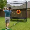 Golfi löögivõrk pallitagastussüsteemiga sise- ja välitreeninguks | E-pood Tootemaailm Golfimängija lööb palli koduses aias treeningvõrku sihtmärgi suunas