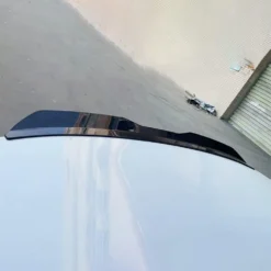 Must läikiv autospoiiler või tagaserv tiival, paigaldatuna heledale auto pinnale
