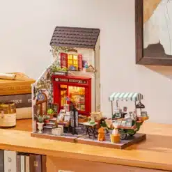 Miniatuurne raamatupood punase fassaadi, valgustatud akende, rohelise kohvikäru ja väikese koerakujuga.