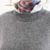 hall pehme vest, mille all on valge särk ja mustriga sall