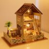 miniatuurne nukumaja kahe korruse ja terrassiga, valge mööbel ja detailid, valgustatud interjöör