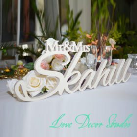 valge puidust silt rooside ja tekstiga 'Mr & Mrs Skahill' laual